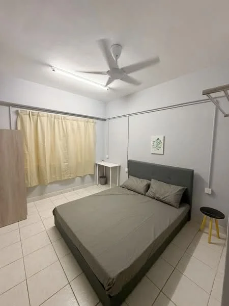 Bedroom features: queen-size bed with grey upholstered headboard, two grey pillows, light grey bedspread, white walls, ceiling fan, window with sheer curtains, white side table, framed artwork on wall, tiled flooring, wooden wardrobe, small yellow stool; style: minimalist.