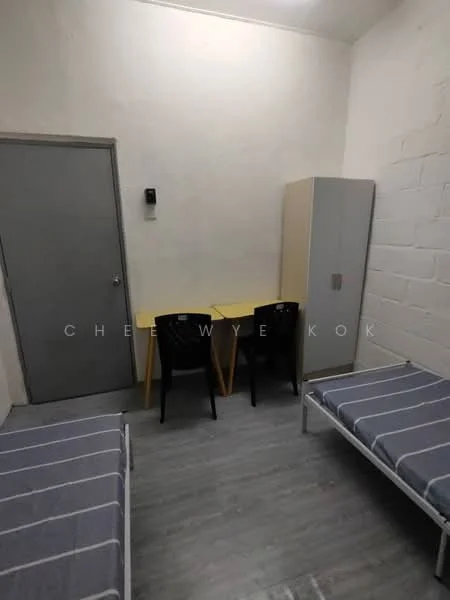 Room features: two single beds with grey bedding, yellow table, two black chairs, grey door, white walls, wooden flooring, built-in wardrobe, wall-mounted intercom, exposed concrete wall; style: minimalist.