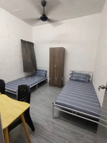 Bedroom features: two single beds with metal frames, striped bedding, wooden wardrobe, ceiling fan, grey laminate flooring, white painted walls, curtain on window, small dining table with black chairs; style: minimalist.