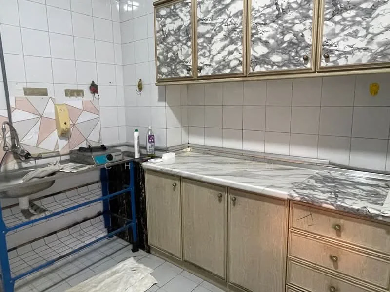 Kitchen features: marble countertop, wall-mounted sink, golden cabinetry, white tiled walls, grey and pink patterned backsplash, blue metal shelving unit, floor tiles, kitchen faucet.