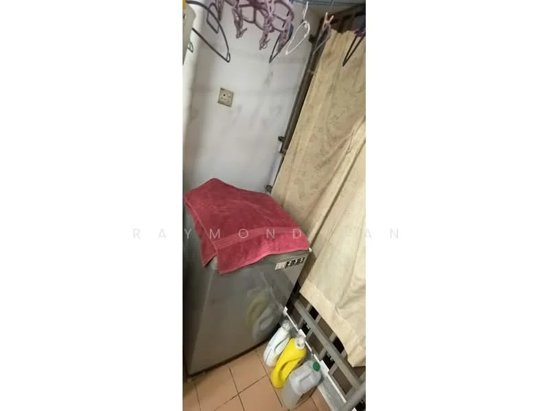 Laundry features: washing machine, grey appliance, pink towel on top, curtain covering, hanging clothes, bottles of detergent, tile flooring, wall-mounted shelf.
