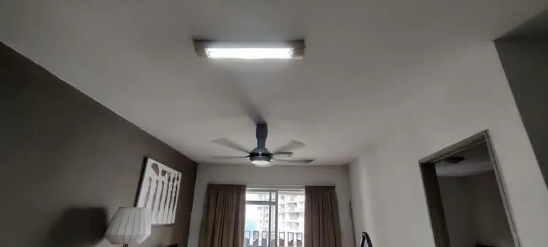 Room features: white painted walls, ceiling with fluorescent light fixture, ceiling fan, floor-to-ceiling windows, curtains, laminate flooring; style: modern; view: city.