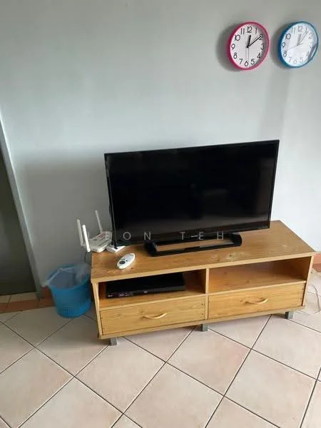 Living features: flat-screen TV, wooden TV console with two drawers, ceramic tile flooring, light grey painted walls, two wall clocks, blue plastic waste basket, router on console.
