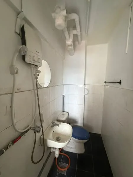 Bathroom features: white tiled walls, black tile flooring, one-piece toilet, round mirror, shower with water heater, sink with faucet, exposed plumbing, towel rack.
