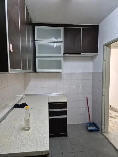 Kitchen features: laminate cabinetry in dark brown, glass-front upper cabinets, white tiled backsplash, grey countertop, single-bowl stainless-steel sink, chrome faucet, tile flooring, wall-mounted light fixture, cleaning supplies visible, open layout to adjacent room; style: modern.