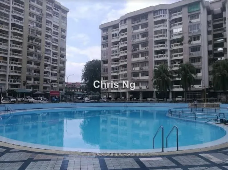 Exterior type: low-rise apartment block; features: swimming pool, surrounding palm trees, paved pool deck, multiple floors of residential units, parking area visible, urban setting, blue water in pool, balconies on residential units; style: modern.