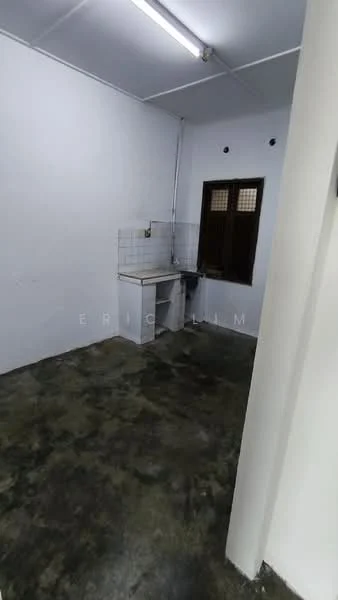 Room features: white painted walls, concrete flooring, single window with wooden grille, kitchen countertop, wall-mounted sink, overhead lighting, no visible appliances, no visible cabinetry; style: minimalist.