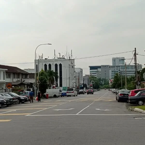 Exterior features: street view, multiple parked cars, urban setting, commercial buildings in background, power lines, sidewalk, traffic lights, road markings; style: modern.