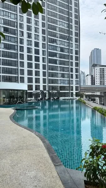 Exterior type: high-rise condominium; features: infinity pool, pool deck with loungers, glass curtain wall facade, surrounded by landscaping, tropical landscaping, manicured lawn, city skyline in background; style: modern.