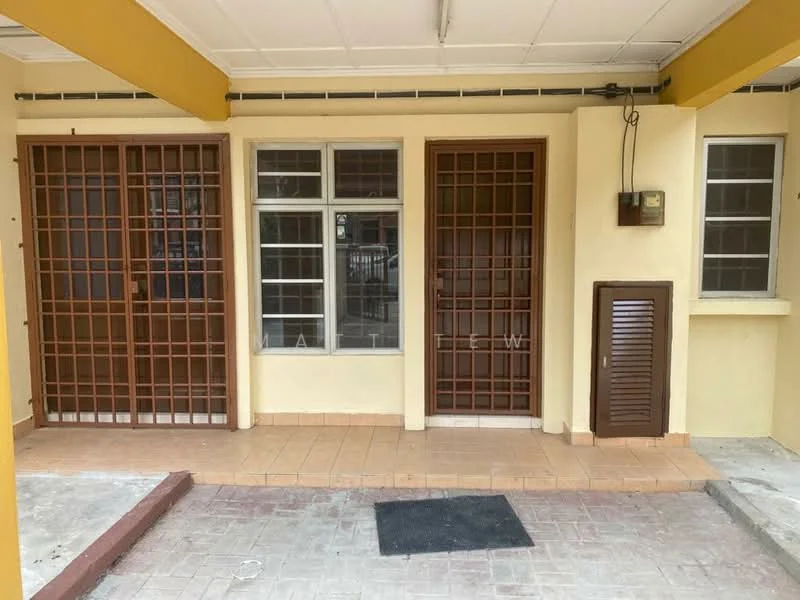 Exterior type: linked terrace house; features: yellow painted facade, brown metal grilles on doors, brown wooden doors, tiled flooring, concrete walkway, window with metal grilles, light fixture on wall, utility box on wall; style: traditional.