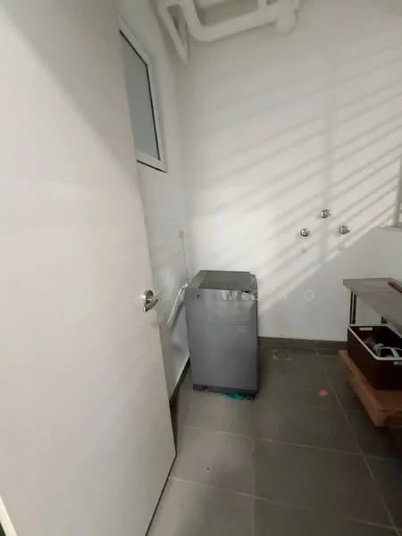 Laundry features: grey front-load washing machine, white painted walls, grey tile flooring, single door, window with blinds, exposed pipes, utility sink, wooden storage cabinet.
