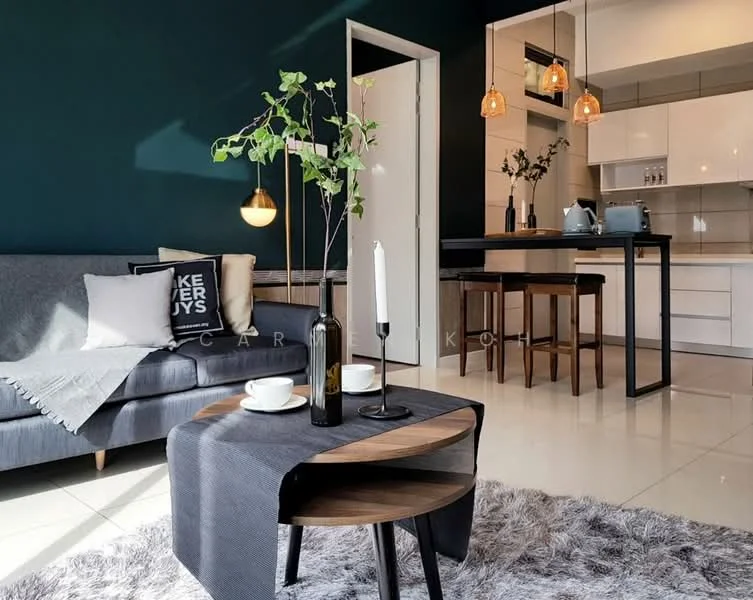 Living features: grey fabric sofa, black and white decorative pillow, round wooden coffee table, white ceramic cups, black table runner, green plant in vase, candle holder with candle, area rug with fluffy texture, pendant lighting with warm bulbs, open kitchen area in background, bar stools at kitchen counter, white cabinetry, light-colored countertop; style: modern.