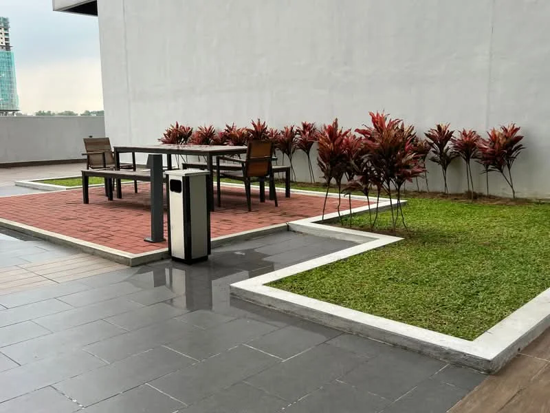 Exterior type: landscape garden; features: paved walkway, outdoor dining table with chairs, manicured lawn, decorative shrubs, concrete trash bin, grey tiled flooring, white stone border; style: modern.