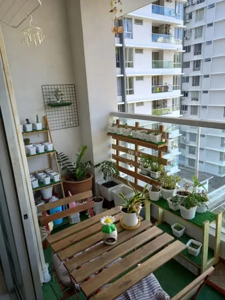 Balcony features: wooden outdoor dining table, 2 wooden chairs, green artificial grass flooring, potted plants, hanging plants, wooden planter box, metal wall grid with plants, glass railing, decorative ceramic pot, chandelier, urban view; style: modern; view: city.