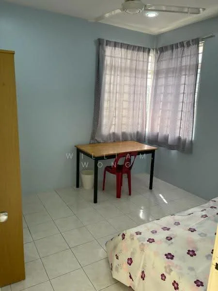 Bedroom features: light blue painted walls, white tiled flooring, single bed with floral bedding, wooden wardrobe, desk with black legs, wooden tabletop, red plastic chair, two large windows with sheer curtains, ceiling fan with light.