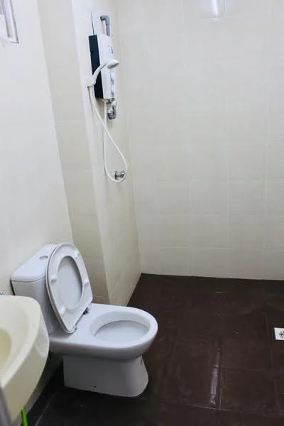 Bathroom features: white ceramic toilet, chrome basin mixer faucet, shower with handheld showerhead, wall-mounted shower control, cream tiled walls, dark brown tiled flooring, built-in shower shelf, small floor drain; style: modern.