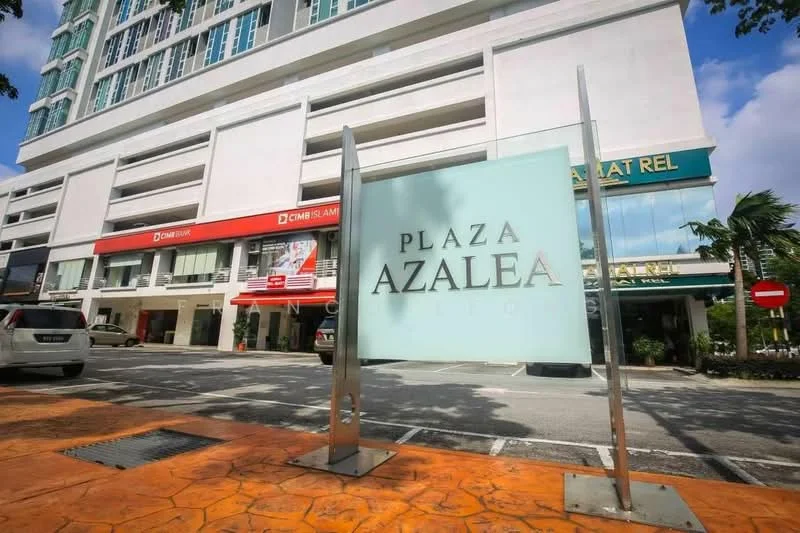 Exterior type: mixed-use development; features: glass facade, signage with 'Plaza Azalea', two-storey building, paved walkway, landscaped area with palm trees, parking spaces visible, street view, surrounding commercial units; style: modern.