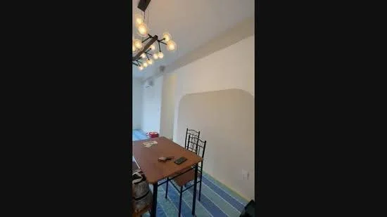 Dining features: wood dining table, black dining chairs, chandelier with multiple bulbs, air conditioning unit, light-colored walls, blue striped rug, decorative wall arch, flooring not visible; style: modern.