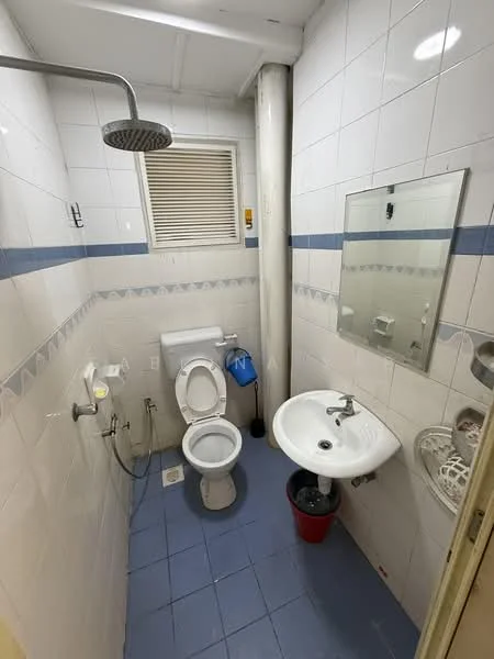 Bathroom features: white tiled walls, blue accent tiles, blue ceramic floor tiles, one-piece toilet, chrome basin mixer faucet, round sink, framed mirror, shower head with adjustable height, shower hose, toilet paper holder, waste bin.