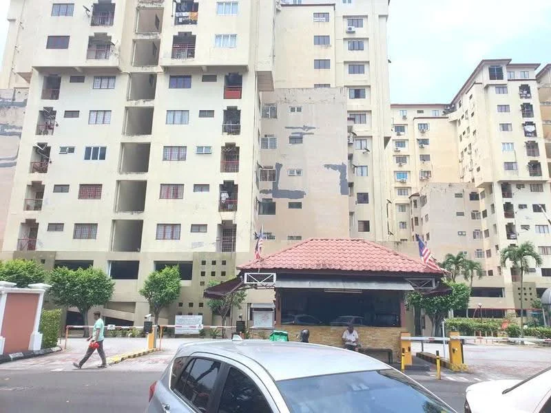 Exterior type: mid-rise condominium; features: cream painted facade, multiple storeys, balconies visible, security guard house at entrance, paved driveway, landscaped greenery, flag poles with flags, visible parking area; style: modern.