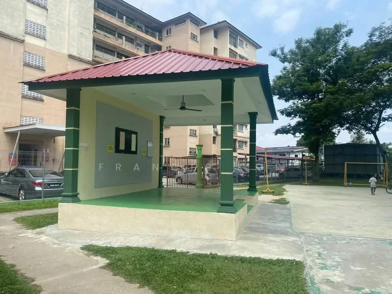 Exterior type: clubhouse; features: gabled roof with red tiles, green columns, open pavilion structure, concrete flooring, manicured lawn, surrounding parking area, fenced perimeter, adjacent sports court; style: modern.
