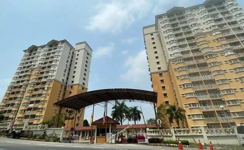Exterior type: mid-rise condominium; features: two connected towers, yellow painted facade, covered entrance with awning, landscaped garden area, palm trees, parking area visible, security guard house at entrance, multiple balconies on each floor; style: modern.