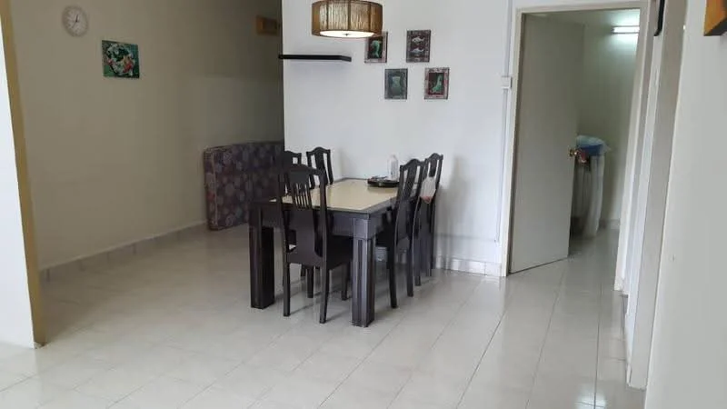 Dining features: dining table with 6 chairs, wall clock, framed artwork on walls, cream painted walls, tile flooring, ceiling light fixture, sofa in background, open doorway to kitchen, white door, trash bin visible in kitchen. Room features: tile flooring, cream painted walls, open doorway.