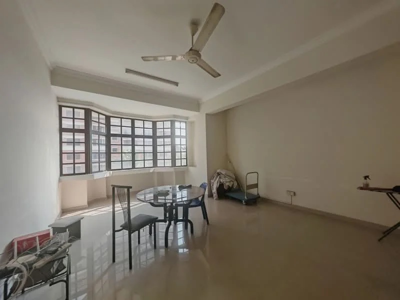 Living features: large bay windows, white painted walls, polished floor tiles, ceiling fan, round dining table, four black dining chairs, folding chair, unmade bed, small side table, natural light from windows.