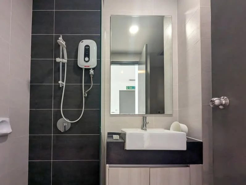 Bathroom features: black countertop, white square sink, chrome basin mixer faucet, wall-mounted showerhead, handheld shower, white tiled walls, dark grey accent wall, large mirror, built-in storage cabinet, light fixture, toilet paper holder; style: modern.