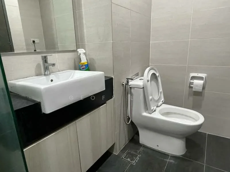 Bathroom features: white ceramic toilet, single-sink vanity with square basin, black countertop, light grey wall tiles, dark grey floor tiles, mirror above sink, toilet paper holder, cleaning spray bottle, glass shower enclosure; style: modern.