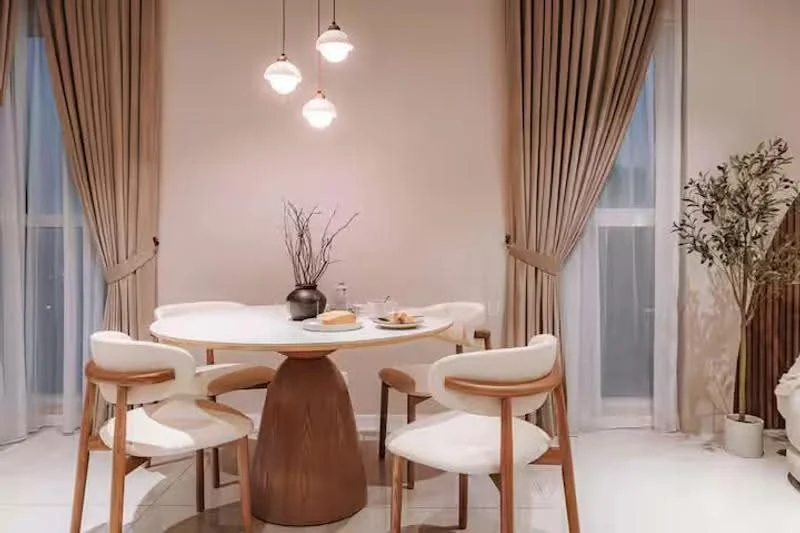 Dining features: round dining table with wooden base, 4 upholstered dining chairs in white, 3 pendant lights with glass shades, floor-to-ceiling windows with sheer curtains, cream painted walls, decorative plant in ceramic pot, light-colored flooring, neutral-toned decor; style: modern.