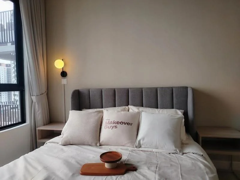 Bedroom features: king-size bed, upholstered headboard in grey, white bedding with decorative pillows, wooden bedside tables, wall-mounted sconce light, floor-to-ceiling window, curtains, neutral painted walls; style: modern; view: city.