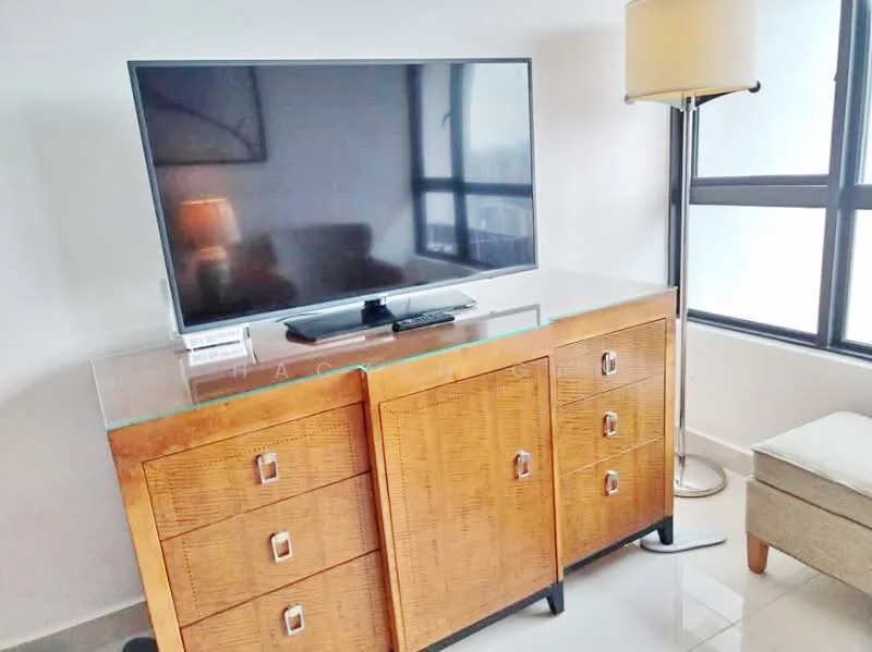 Room features: flat-screen TV on stand, wooden cabinet with drawers, glass top on cabinet, floor lamp, neutral-colored armchair, large windows with black frames, light-colored flooring, decorative items on cabinet; style: modern.