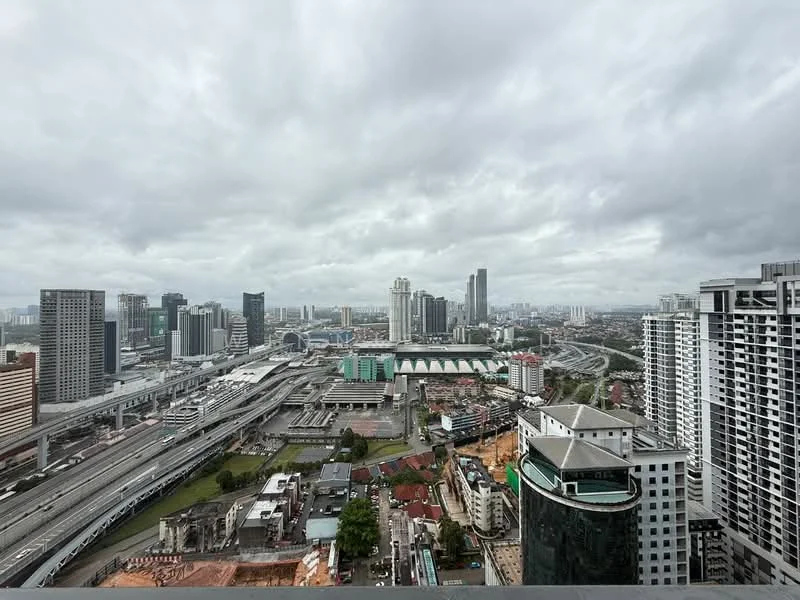 Exterior type: high-rise condominium; features: city skyline view, surrounded by urban landscape, multiple high-rise buildings, highway visible, green spaces in the foreground, cloudy sky, modern architecture, commercial buildings, residential buildings; style: modern.