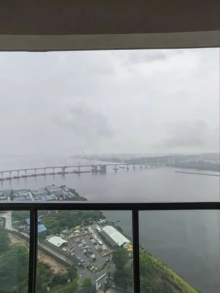 Exterior type: high-rise condominium; features: city skyline view, waterfront view, bridge visible, surrounded by greenery, industrial area in distance; style: modern.