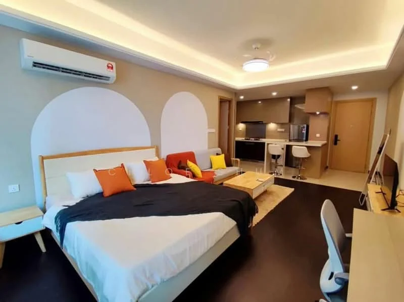 Room features: queen-size bed with white bedding, upholstered headboard, decorative cushions in orange and yellow, 2-seater fabric sofa in red, coffee table, TV console, wall-mounted TV, wooden flooring, recessed ceiling lights, 1 wall-mounted split AC, kitchenette with grey cabinetry, stainless-steel fridge, built-in oven, bar stools at kitchen counter, desk with chair; style: modern.