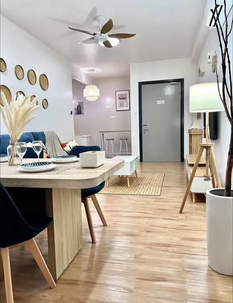 Living features: wooden flooring, 5-blade ceiling fan, wall-mounted TV, sofa in blue fabric, dining table with wooden top, upholstered dining chairs, decorative wall plates, area rug, floor lamp, light fixture, open shelving unit, neutral wall color, door with handle, window with blinds; style: modern.