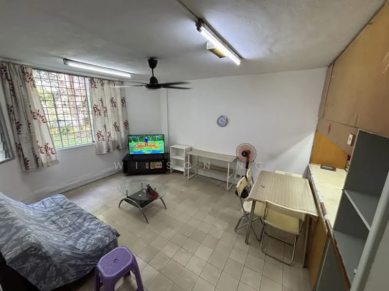 Living features: grey fabric sofa bed, glass coffee table, wall-mounted TV, ceiling fan, dining table with four chairs, wall-mounted clock, window with sheer curtains, tile flooring, white painted walls, kitchenette with countertop.