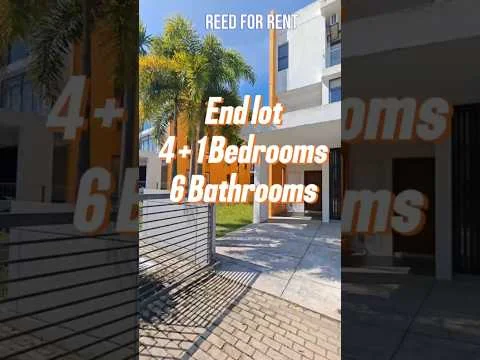 Exterior type: end lot house; features: paved walkway, landscaped garden, palm trees, two-storey building, orange painted facade, large windows, metal gate, fenced perimeter; style: modern.