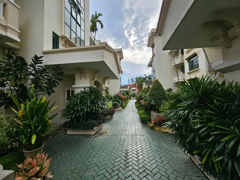 Exterior type: low-rise apartment block; features: manicured pathway, landscaped garden with shrubs, paved walkway with herringbone pattern, tropical plants, greenery along the pathway, two-storey buildings, balconies on upper floors, clear sky in background; style: modern.