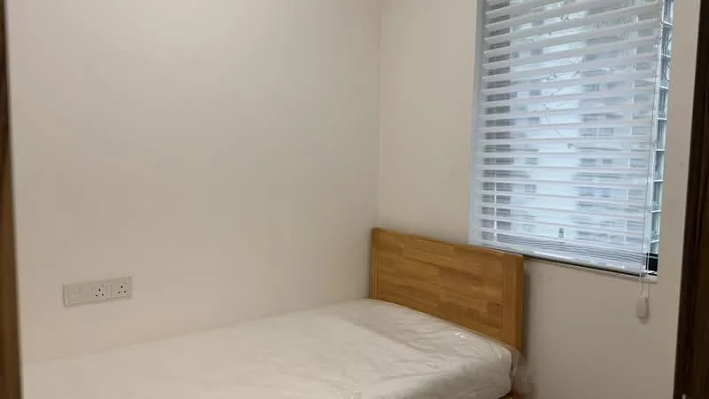 Bedroom features: single bed, wooden bed frame, white bedding, white painted walls, window with blinds, light-colored flooring, power outlets on wall.