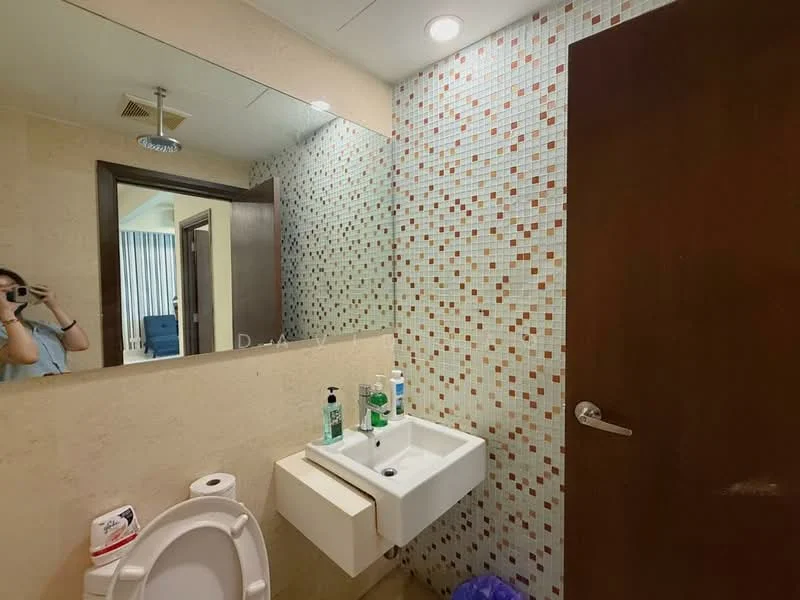 Bathroom features: mosaic tile wall, cream painted walls, single-sink vanity with wall-mounted cabinet, chrome basin mixer faucet, framed mirror, one-piece toilet, recessed ceiling lights, tile flooring, hand soap dispenser, toothbrush holder, waste bin; style: modern.
