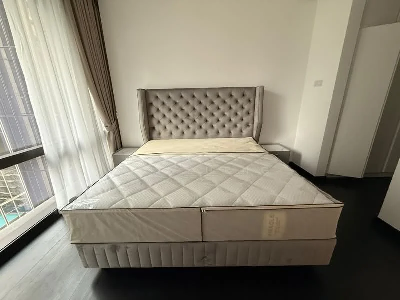 Bedroom features: king-size bed, upholstered headboard with tufted design, floor-to-ceiling windows, sheer curtains, dark wood flooring, built-in wardrobe, nightstands, mattress without bedding; style: modern; view: city.