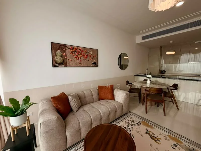 Living features: beige fabric sofa with orange cushions, round wooden coffee table, area rug with floral pattern, framed artwork on wall, potted plant, dining table with wooden chairs, recessed ceiling lights, white painted walls, large windows with natural light, open layout to kitchen area; style: modern.