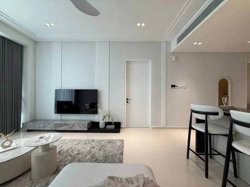 Living features: light grey walls, white ceiling with recessed downlights, large floor-to-ceiling windows with sheer curtains, light-coloured sofa, round coffee table, TV console with wall-mounted TV, decorative wall paneling, area rug with neutral tones, bar stools at kitchen counter, open layout to dining area; style: modern.