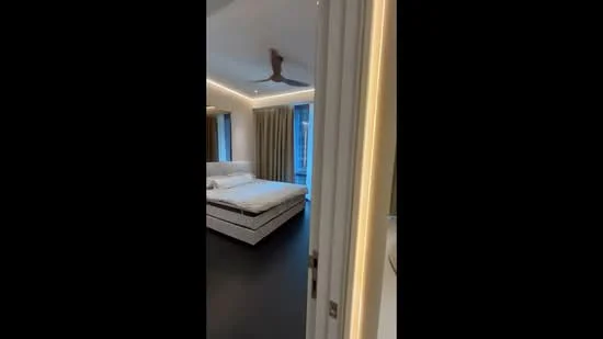 Bedroom features: king-size bed, upholstered headboard, bedside lamps, floor-to-ceiling windows, curtains, 5-blade ceiling fan, recessed LED downlights, dark wood flooring, decorative wall lighting, built-in wardrobe; style: modern; view: city.