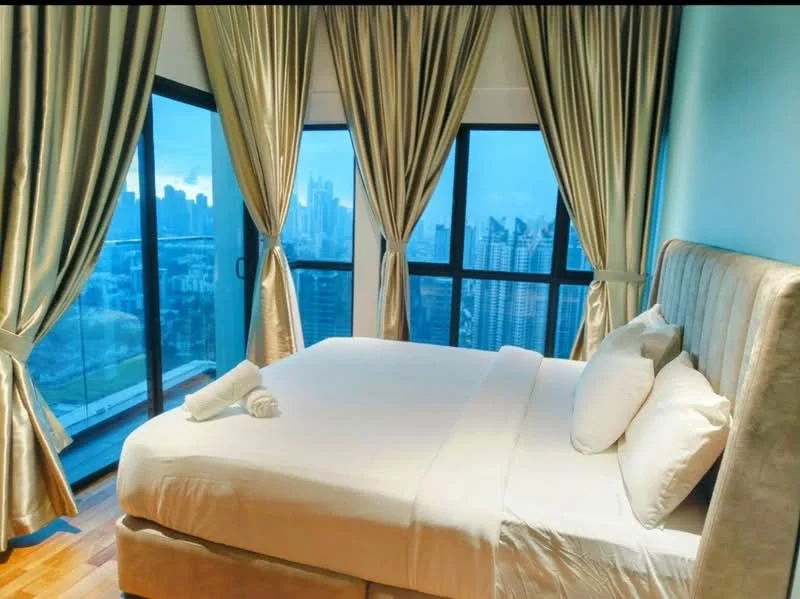 Bedroom features: king-size bed with upholstered headboard, white bedding, floor-to-ceiling windows, sheer curtains, blackout curtains, wooden flooring, city skyline view, decorative towels, nightstand, table lamp; style: modern; view: city.