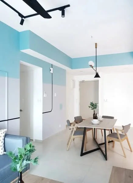 Dining features: dining table with black metal frame, 4 wooden dining chairs, pendant light fixture, light blue painted walls, grey painted walls, white ceiling, ceiling fan, decorative plant on table, wall-mounted electrical outlet, open doorway leading to another room, flooring with light-colored tiles; style: modern. Living features: grey fabric sofa, decorative throw pillows, area rug, wall-mounted light fixture; style: modern.