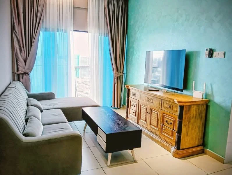 Living features: grey fabric 3-seater sofa, wooden coffee table with black top, wooden TV console with drawers, wall-mounted flat-screen TV, floor-to-ceiling windows, sheer curtains, blackout curtains, light-coloured tiled flooring, textured green accent wall, decorative wall paneling; style: modern; view: city.