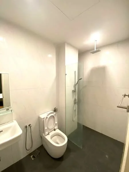 Bathroom features: white tiled walls, grey tile flooring, glass shower enclosure, rain shower head, handheld shower, single-sink vanity, framed mirror, one-piece toilet, chrome basin mixer, recessed ceiling lights; style: modern.